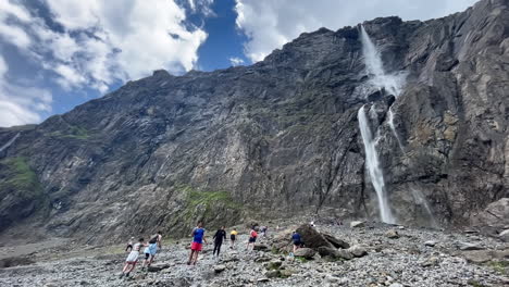 Gente-Caminando-Por-El-Río,-Para-Llegar-A-La-Gran-Cascada-Del-Circo-De-Gavarnie,-Famoso-Paisaje-Francés-De-Las-Montañas-De-Los-Pirineos