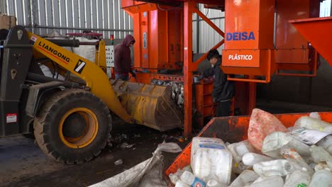 Vista-Media-De-Los-Trabajadores-Que-Cargan-Desechos-Compactados-En-Una-Excavadora-Dentro-De-Una-Planta-De-Procesamiento-De-Desechos