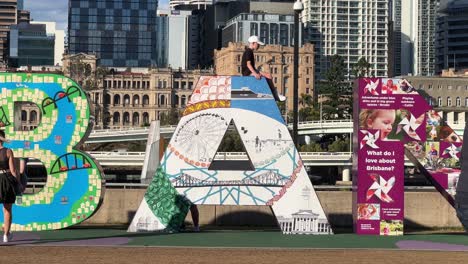 Menschen,-Die-Fotos-Mit-Dem-Riesigen-Bunten-Blockbuchstaben-Von-Brisbane-Machen,-Dem-Ikonischen-Wahrzeichen-Am-Flussufer-In-Der-Innenstadt-An-Einem-Sonnigen-Tag,-Queensland,-Der-Sonnenscheinstaat,-Australien,-Nahaufnahme