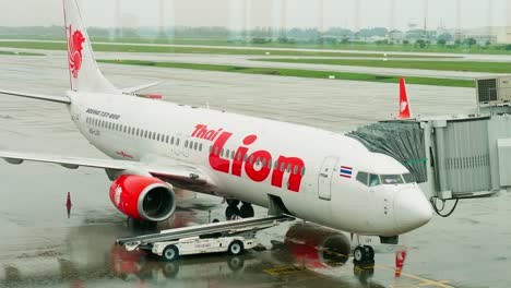 Thai-Lion-Airlines-Docken-An-Der-Halle-An,-Während-Sie-Sich-An-Einem-Regnerischen-Tag-Mit-Bodenpersonal-Auf-Dem-Internationalen-Flughafen-Don-Mueang-dmk-Auf-Den-Abflug-Vorbereiten