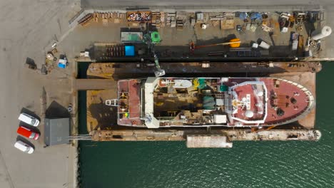 An-aerial-view-of-a-fishing-trawler-lifted-out-of-the-water-and-into-a-dry-dock-for-repair-and-painting-jobs-in-Hanstholm