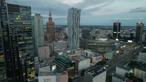 Vista-Aérea-Del-Centro-Financiero-De-Śródmieście-De-Noche-Con-Emblemáticos-Rascacielos-En-Polonia