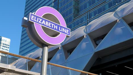 Canary-Wharf,-London,-Großbritannien---August-2022---Ein-Zeichen-Der-Neuen-Elizabeth-linie-In-Canary-Wharf-Neben-Dem-Crossrail-Place-Dachgarten-An-Einem-Sonnigen-Sommermorgen