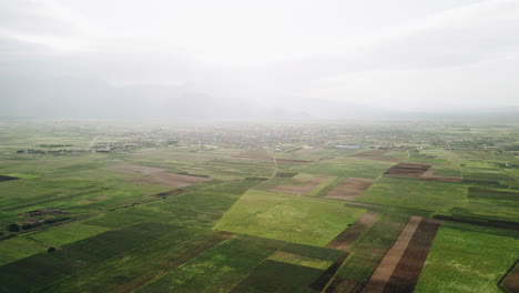 Cinematic-aerial-view-of-agricultural-fields-and-a-small-city