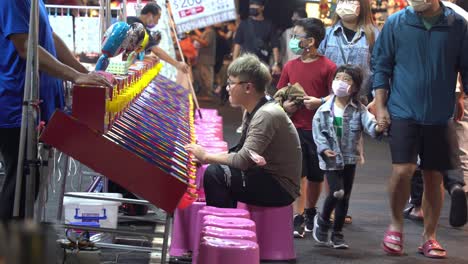 Local-street-shot-of-a-male-adult-having-fun-playing-classic-pinball-game-at-gaming-stall-at-famous-night-market-in-Taiwan,-Asia