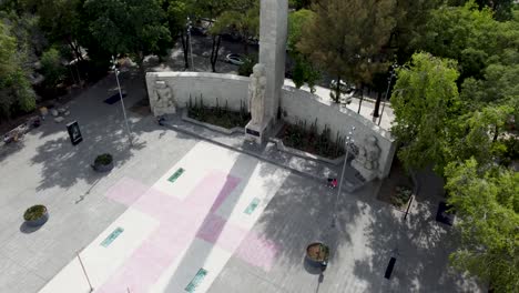 Crane-Shot-Revealing-the-Monument-to-the-Mother-with-a-Bunch-of-Beautiful-Green-Treetops-and-Several-Buildings-Behind-in-Mexico-City