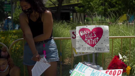 Un-Par-De-Manifestantes-De-Blm-Se-Paran-Junto-A-Los-Carteles-De-Black-Lives-Matter-Adjuntos-A-Una-Cerca-En-El-Centro-De-La-Ciudad