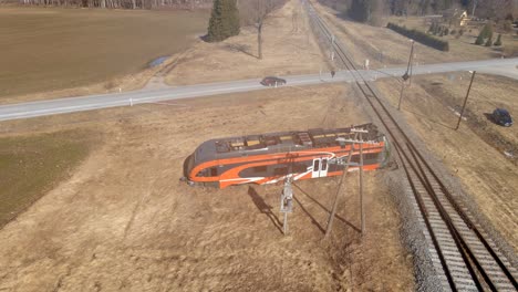 Drone-shot-of-Elron-train-wreck-next-to-railway-while-cars-crossing-railway-on-backround