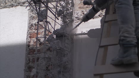 Angle-4-of-Man-with-a-hammer-drill-eliminatin-a-portion-of-an-old-wall-in-a-construction-site,-in-Full-Hd-slowmotion-at-60fps