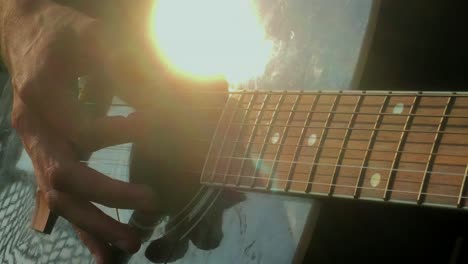 CLOSE-UP-of-man-playing-Hotel-California-on-guitar-with-sun-reflected-in-the-guitar