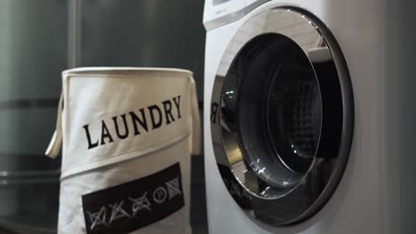 4k-Stationäre-Aufnahme-Eines-Mannes,-Der-Wäsche-Wäscht-Und-Weiße-Wäsche-In-Eine-Waschmaschine-Wirft