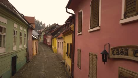 Beautiful-view-of-the-colorful-houses-and-a-person-walking-by-the-old-stone-paved-street-of-the-Sighisoara-medieval-town