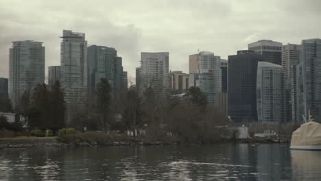 Wide-panning-shot-of-Sea-plane-landing-behind-trees-in-Downtown-Vancouver-on-cloudy-morning