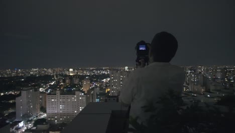 Hombre-Fotografiando-El-Horizonte-De-São-Paulo-Una-Noche-Filmada-En-4k-Uhd