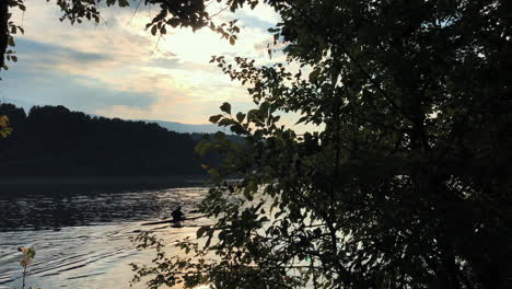 Shadowed-view-through-the-trees-of-two-kayakers-paddling-along-the-river