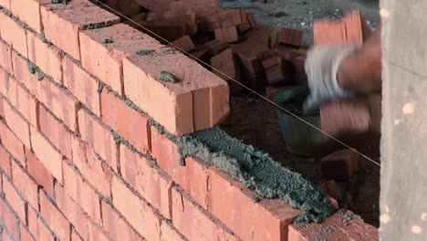 Hombre-Asiático-Poniendo-Ladrillos-Encima-Del-Mortero-Para-Construir-Una-Pared