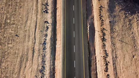 Flying-Along-a-Desert-Road-with-Vertical-Panning-to-Reveal-a-Hot,-Dry-Landscape