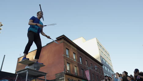 Hombre-Cinematográfico-Haciendo-Malabares-Con-Espadas-Frente-A-Una-Multitud-De-La-Ciudad