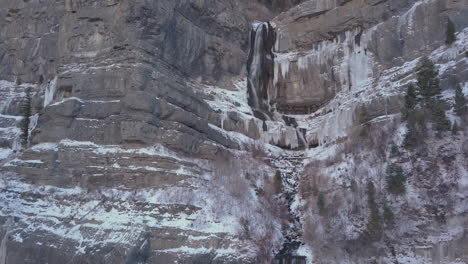 A-beautiful-waterfall-half-flowing-and-half-frozen-in-rugged-mountain-terrain