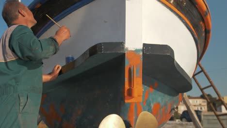 El-Pintor-Revela-Una-Foto-De-Un-Pescador-Griego-Pintando-Una-Moldura-De-Madera-De-Un-Barco-De-Pesca-Construido-En-Carvel-Cinemática-A-Cámara-Lenta.