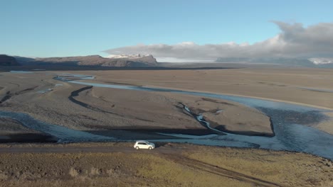 Aerial-Shot-of-a-Car-Parked-Above-a-Glacial-River-System