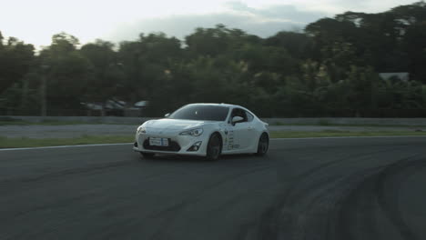 Coche-De-Carreras-Blanco-A-La-Deriva-Y-Conduciendo-Por-Una-Pista-De-Deportes-De-Motor