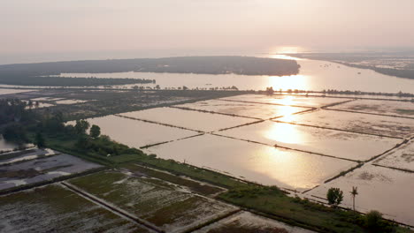 Drone-flies-high-and-after-farms-and-salt-plantations,-the-Cambodian-Ocean-comes-to-into-view