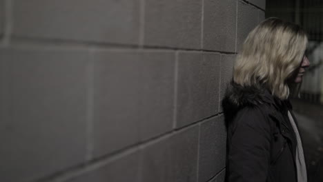 Girl-leans-against-a-wall-in-an-alley-at-night