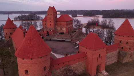 AERIAL:-Establishing-Shot-of-Gotic-Style-Medieval-Trakai-Island-Castle-Gates-and-Towers-with-Lithuanian-Flag-Waving-on-Top-of-Gate-Tower