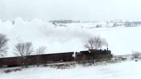 Plano-General-Aéreo-De-Un-Motor-De-Vapor-Restaurado-Tirando-De-Automóviles-De-Pasajeros-A-Través-Del-Paisaje-Cubierto-De-Nieve