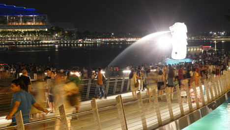 Singapur---Alrededor-De-La-Gente-Caminando-En-Un-Puente-Lleno-De-Gente-Junto-A-La-Fuente-Merlion-En-Singapur-Por-La-Noche