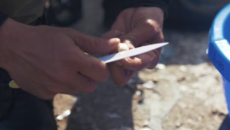 Close-up-cutting-garlic-outdoors-with-knife-in-sunshine