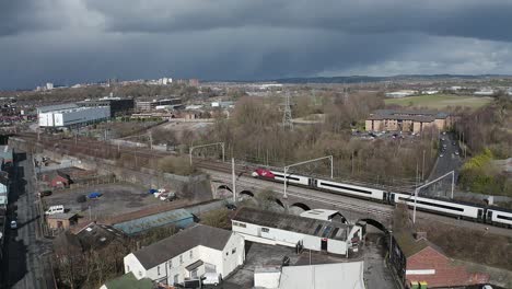 Aerial-footage-of-trains-approaching-Stoke-on-Trent-train-station-in-the-midlands-by-the-canal,-waterside-and-A50-motorway