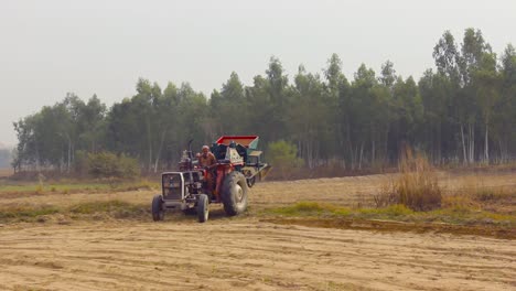 Un-Agricultor-Opera-Su-Tractor-En-El-Campo-Cerca-De-Un-Bosque-De-Eucaliptos