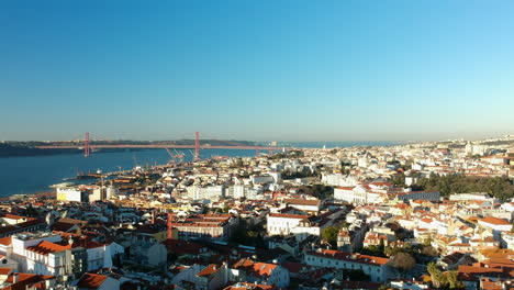 Vista-Aérea-De-La-Ciudad-De-Lisboa-Con-El-Famoso-Puente-Ponte-25-De-Abril-Y-Cristo-Rei-Al-Fondo,-Lisboa,-Portugal