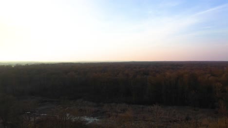 [DRONE]-wide-orbiting-shot-of-a-swamp-in-the-middle-of-woods-with-a-sunset-in-the-background