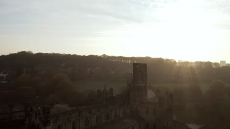 Aerial-Tracking-Shot-of-Kirkstall-Abbey-at-Dawn-with-Lens-Flare-on-Sunny-Spring-Day-facing-Sun