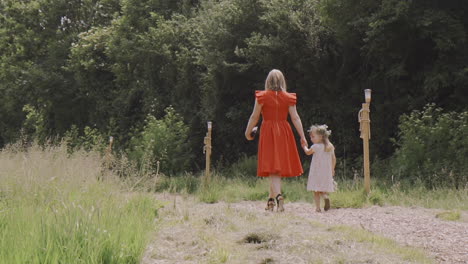 Mother-and-daughter-walking-hand-in-hand-through-a-field