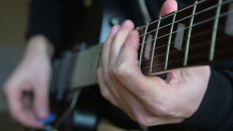 Man-Practising-a-vintage-black-electric-guitar,-rehearsing-chords,-solos-and-octaves-in-a-natural-light-environment.