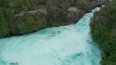 Aerial-drone-shot-of-spectacular-waterfall-Hukas-Falls-and-tourists-at-viewpoint,-New-Zealand