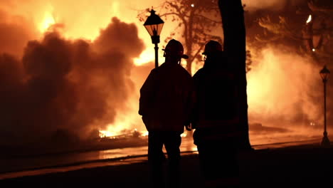 Die-Silhouette-Von-Zwei-Feuerwehrmännern,-Die-Riesige-Flammen-Und-Rauchschwaden-Beobachten,-Die-Vorbeiziehen,-Während-Das-Historische-Shakespeare-theater-In-Stratford,-Ct,-Niederbrennt