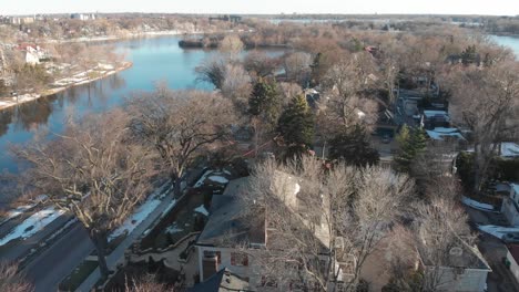 Aerial-footage-going-forward-of-suburbs-in-Minnesota,-lake-behind,-sunny-afternoon,-homes