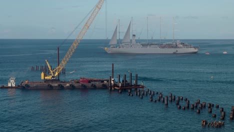 Crane-barge-moving-into-position-at-ship-terminal,-pier,-and-pilings,-under-construction