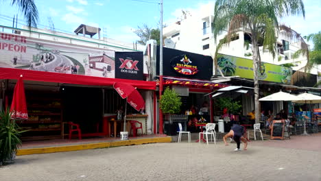 Joven-En-Camiseta-Haciendo-Volteretas-Y-Trucos-De-Breakdance-En-El-Paseo-Marítimo-De-México-Frente-A-Las-Tiendas