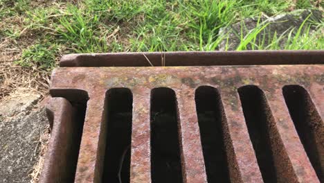 Zooming-in-footage-of-a-rusty-grill-drain-cover
