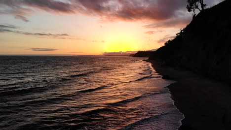 Luftdrohnenaufnahme-Eines-Sonnenunterganghimmels-Mit-Reflexionen-Auf-Den-Meereswellen-In-Der-Nähe-Der-Küstenklippen-Von-Santa-Barbara,-Kalifornien