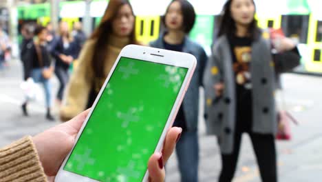 Lady's-hand-holding-phone-in-a-busy-street