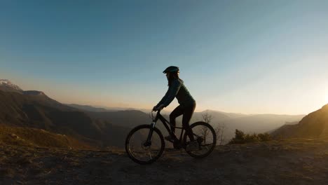 Mädchen,-Die-Bei-Sonnenuntergang-Auf-Dem-Gipfel-Eines-Berges-Fahrrad-Fahren