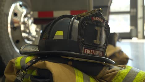 Casco-De-Bombero-En-La-Parte-Superior-Del-Equipo-De-Extinción-De-Incendios-Con-Camión-De-Bomberos-En-Segundo-Plano.