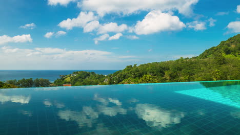 Time-lapse-The-smooth-cloud-movement-reflects-the-surface-of-the-private-swimming-pool-with-green-mountain-scenery-with-the-sky-and-the-sea-on-a-clear-day